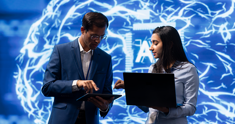 Man and woman stand in front of digital image of AI brain