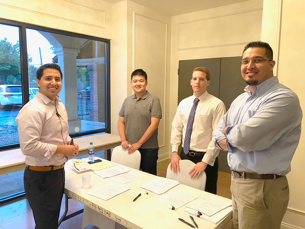 Men stand around a table smiling for the camera