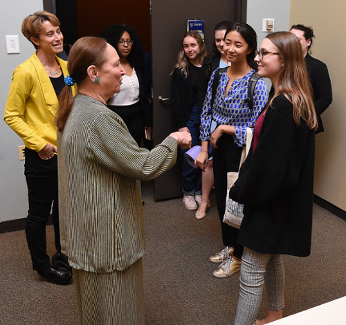 Students and faculty member sit around a table in discussion 